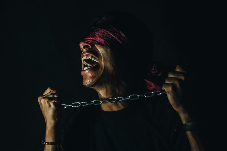 "Corporate Idolatry" by Helena Hawkins - blindfolded person trying to break free from chains